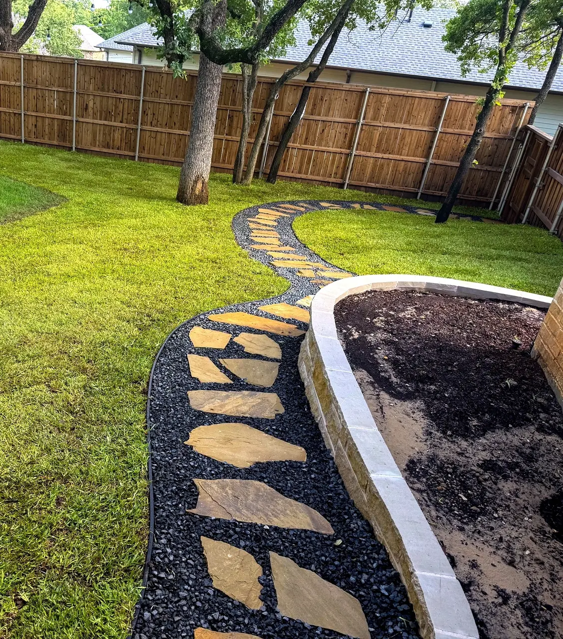 Flagstone path beside a raised planting bed on a Denton County, TX property
