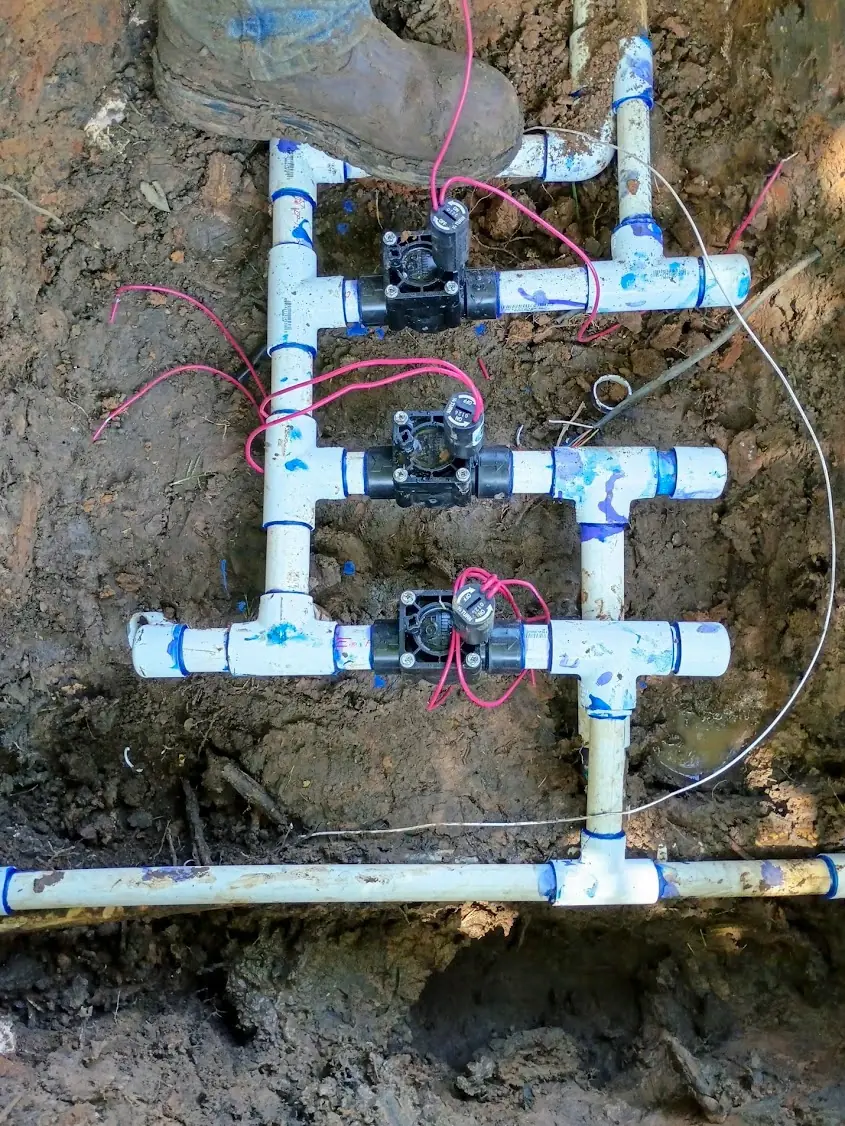 Sprinkler valve manifold uncovered in a trench during an irrigation repair on a Denton County, TX property